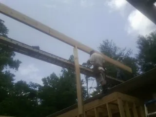 Carpenter setting a ridge beam over a new addition frame — Ice Dam Removal by Roofing Brothers in Port Crane