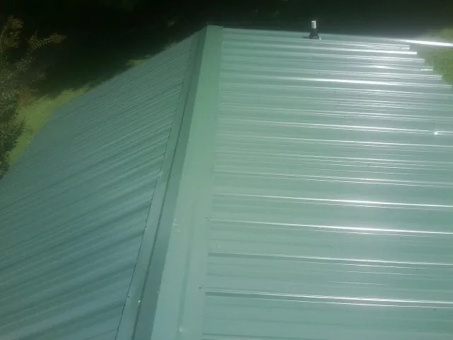 New green metal panels meeting at the ridge of a roof — Flat Roof Repair work by our crew in Port Crane