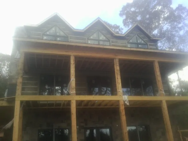 Dormers and porch framing on a large log home under construction — Roof Coating work by our crew in Port Crane