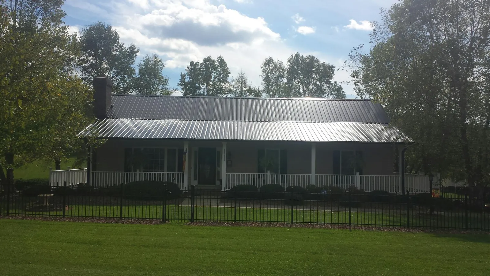 Gray metal roof on a brick ranch with a full width front porch — Gutter Guard Installation work by our crew in Port Crane