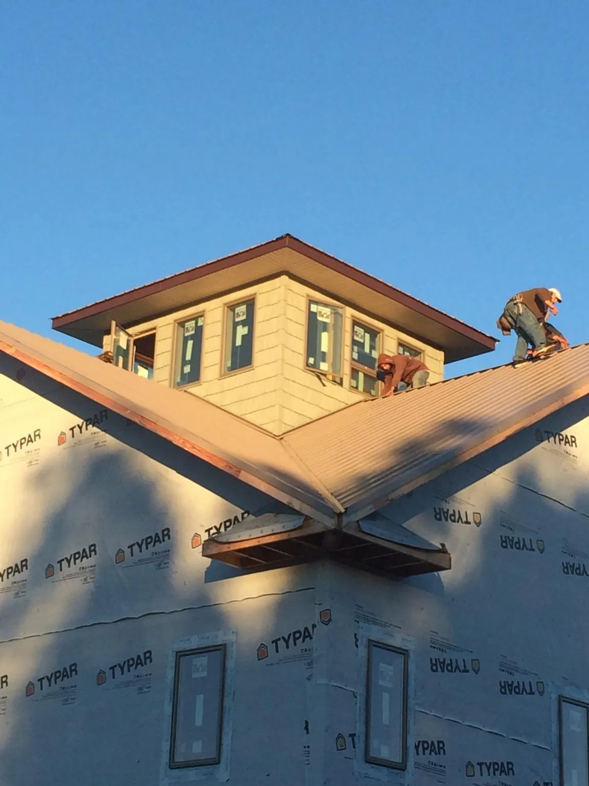 Roofers working around a rooftop cupola on a new metal roof at sunset — Roof Waterproofing in Port Crane by Roofing Brothers